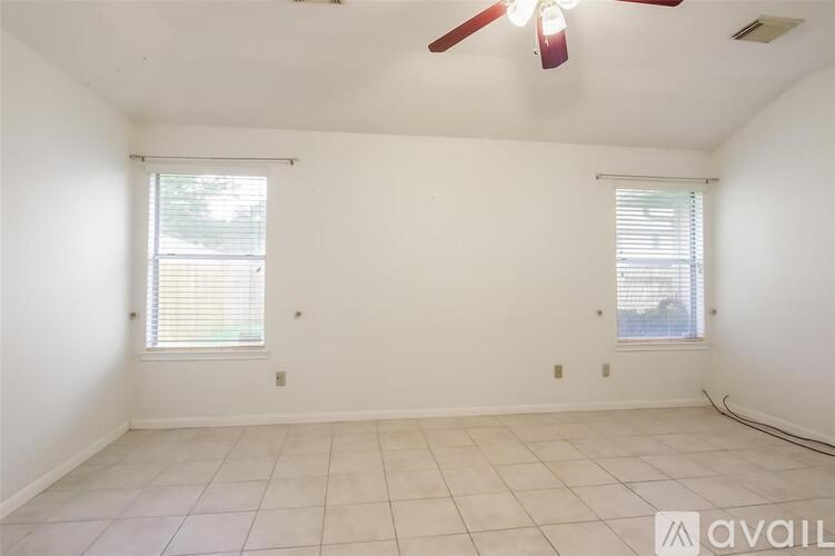 A room with a ceiling fan and two windows.
