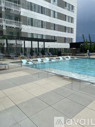A pool area with a tiled floor and a building in the background.