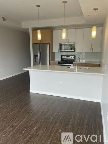 A kitchen with a white counter top and wooden floors.