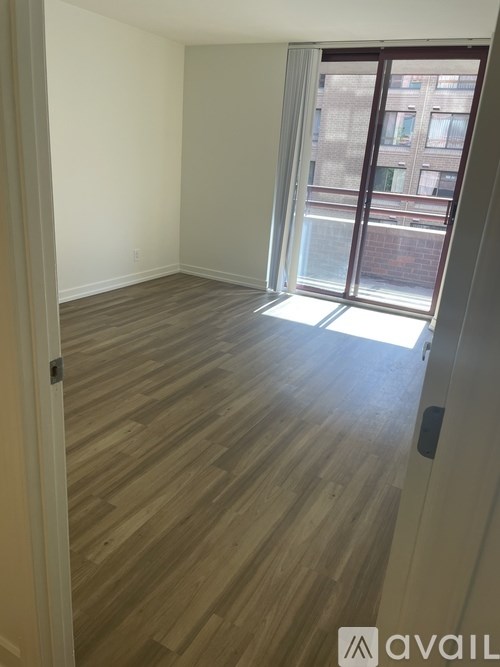 A room with wooden flooring and a sliding glass door leading to a balcony.