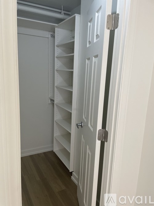 A white door with a grey handle is open to a hallway with a white door on the other side.
