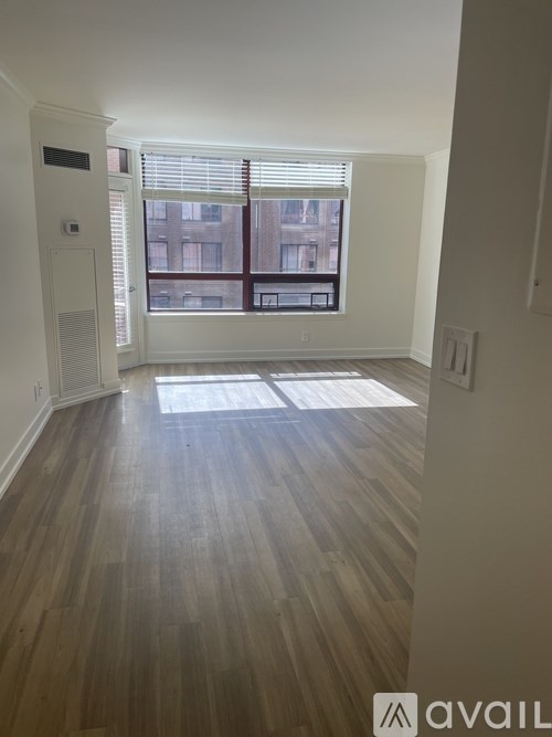 A room with wooden flooring and a window overlooking a cityscape.