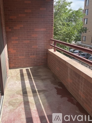 A balcony with a brick wall and a striped tile floor.