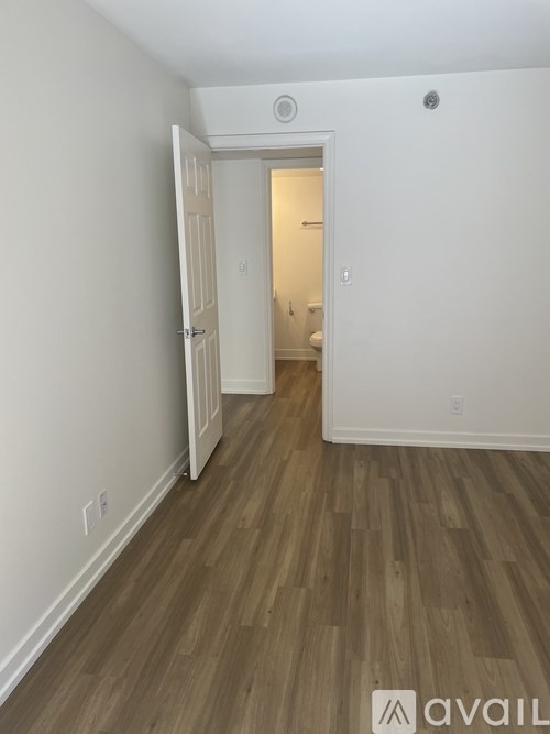 A room with wooden flooring and a doorway leading to another room.
