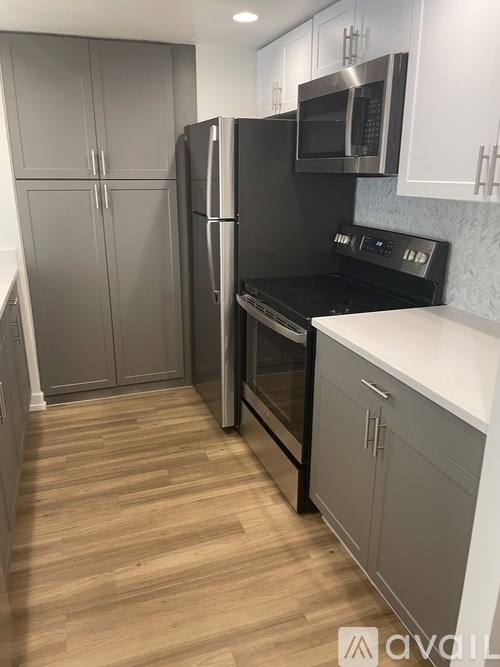A kitchen with a black refrigerator and stove top oven.