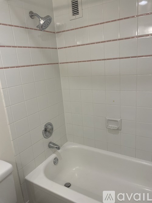 A white bathtub with a shower head above it.