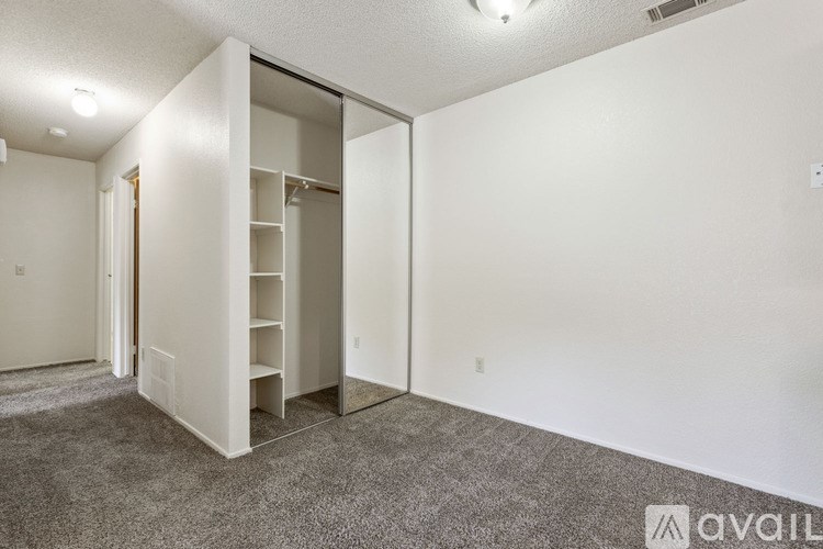 A room with a white wall and a grey carpet.