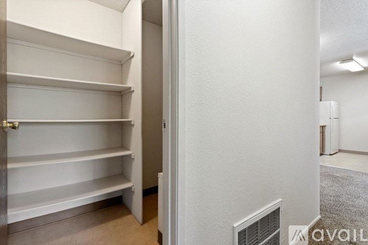 A white closet with shelves and a door leading to a hallway.
