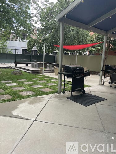 A patio with a grill and a table under a canopy.
