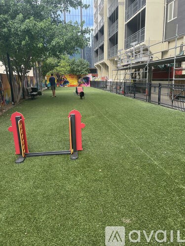 A man is walking his dog in a park with artificial grass.