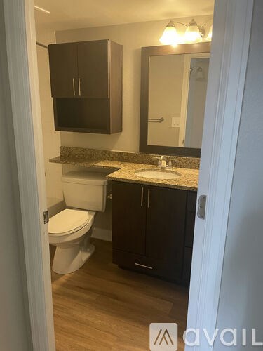 A bathroom with a toilet, sink and cabinets.