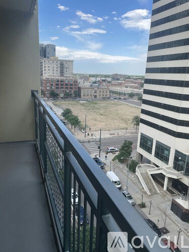 A balcony overlooks a city street with cars and buildings.