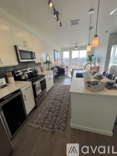A kitchen with white cabinets and a patterned rug on the floor.