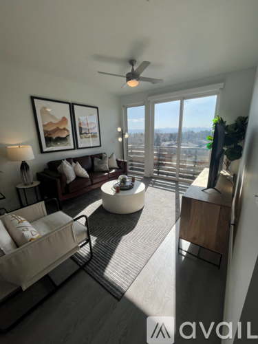 A living room with a sofa, a chair, a coffee table, and a ceiling fan.
