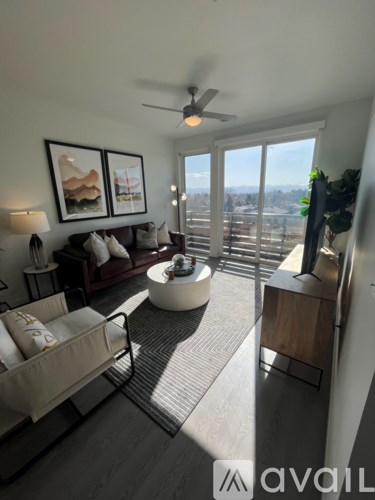 A living room with a sofa, a chair, a coffee table, and a ceiling fan.
