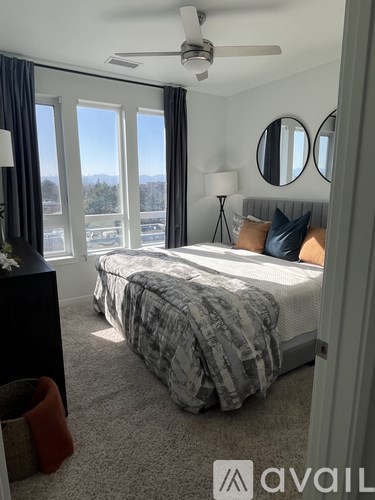 A bedroom with a large bed and a view of the outdoors through the windows.