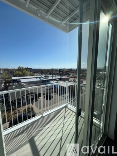 A balcony with a metal railing and glass doors overlooking a parking lot.