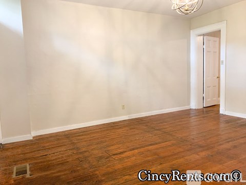 A room with wooden floors and a doorway leading to another room.