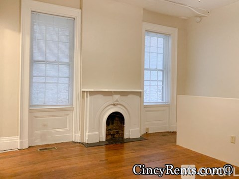 A room with a fireplace and two windows.