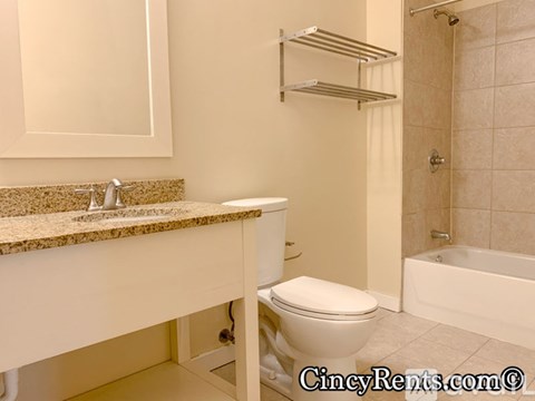 A white toilet is in a bathroom with a sink and a bathtub.