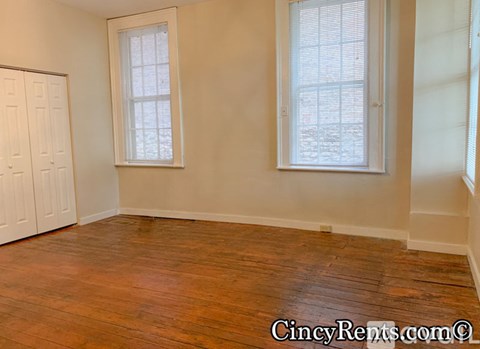 A room with wooden floors and two windows.