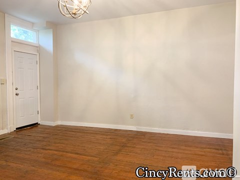 A room with a white door and a wooden floor.