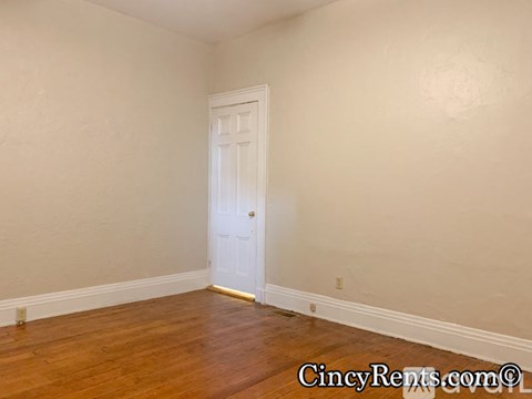 A room with a white door and wooden flooring.