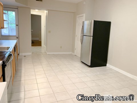 A kitchen with a black fridge and white tiled floor.