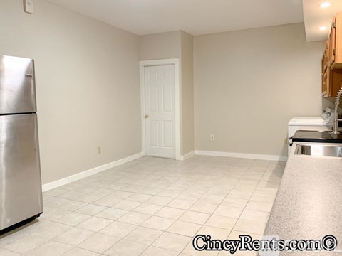A kitchen with a refrigerator, sink, and a door.