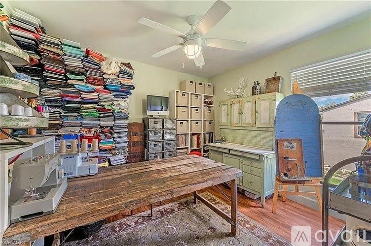 A room with a table, a fan, and a sewing machine.