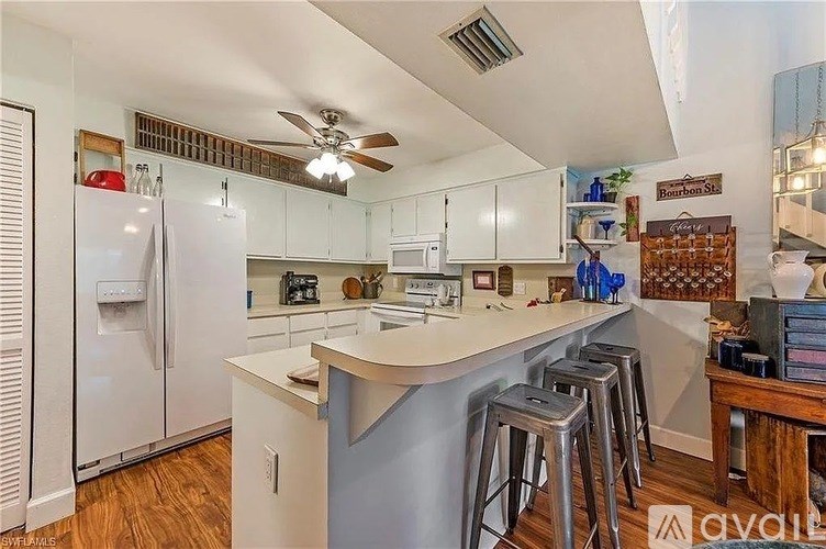 A kitchen with white appliances and a white ceiling fan.