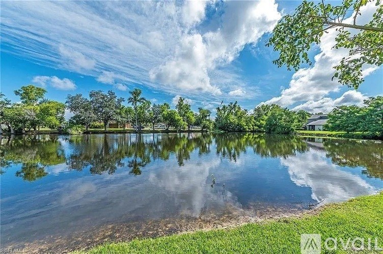 A serene lake surrounded by lush greenery under a partly cloudy sky.