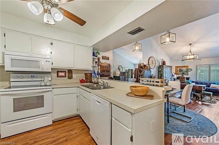 A kitchen with white appliances and wooden floors.