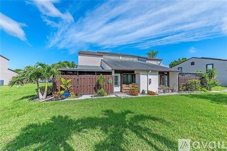 A house with a well-maintained lawn and a clear blue sky above.
