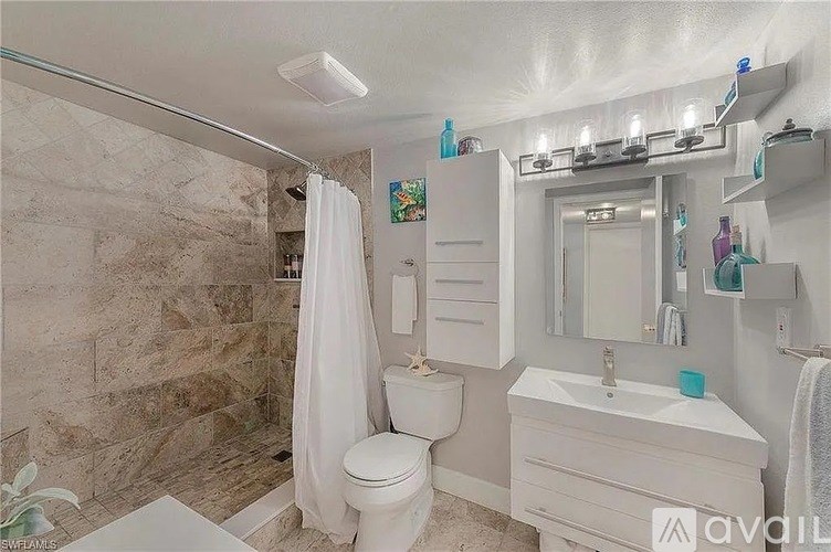 A bathroom with a toilet, sink, and shower area.