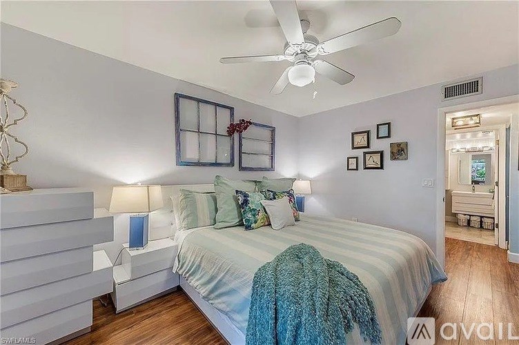 A bedroom with a bed, a ceiling fan, and a nightstand with a lamp.