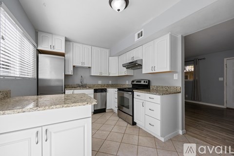 A kitchen with white cabinets and granite countertops.
