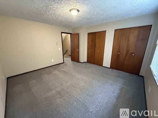 A room with a carpeted floor and three wooden doors.