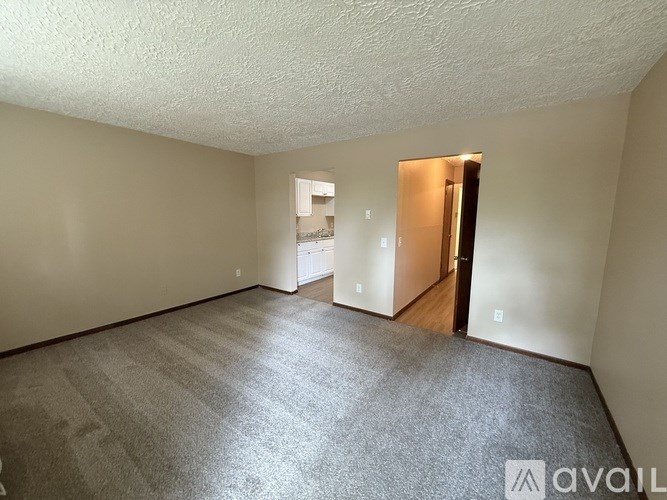 A room with a carpeted floor and a door on the right side.