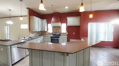 A kitchen with a red wall and a large island in the middle.