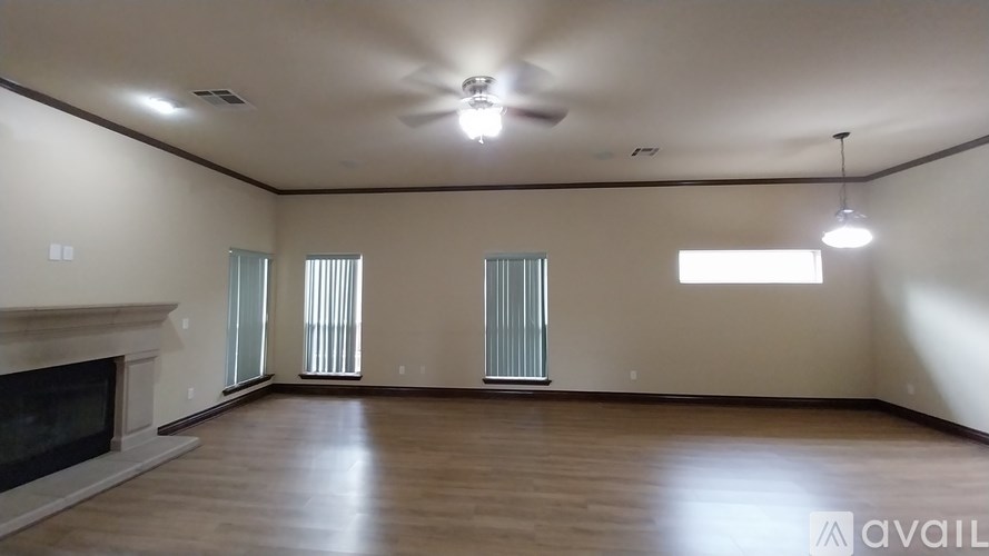 A spacious room with a fireplace and a ceiling fan.