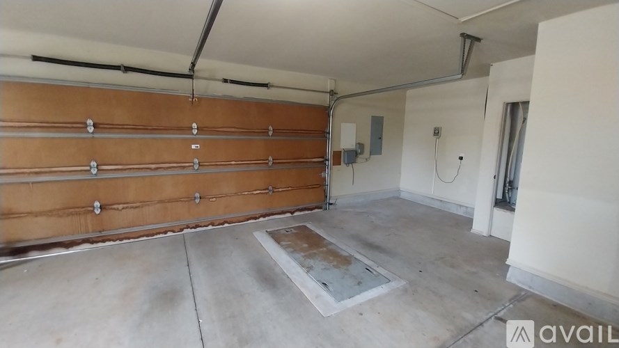 A garage with a brown wooden door and a concrete floor.