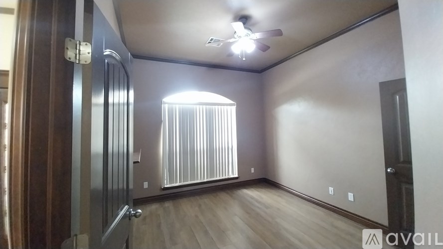 A room with a ceiling fan and a window with vertical blinds.