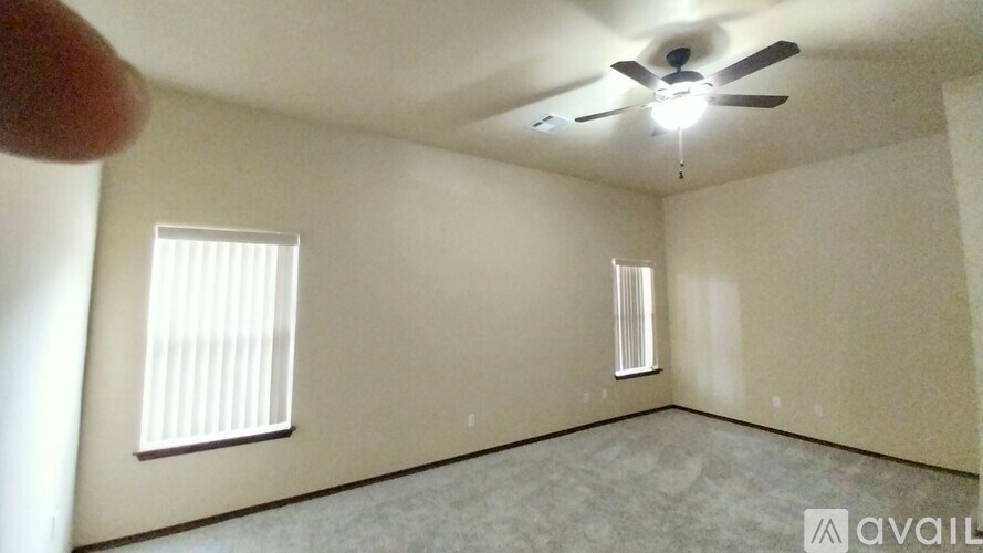 A room with a ceiling fan and two windows.