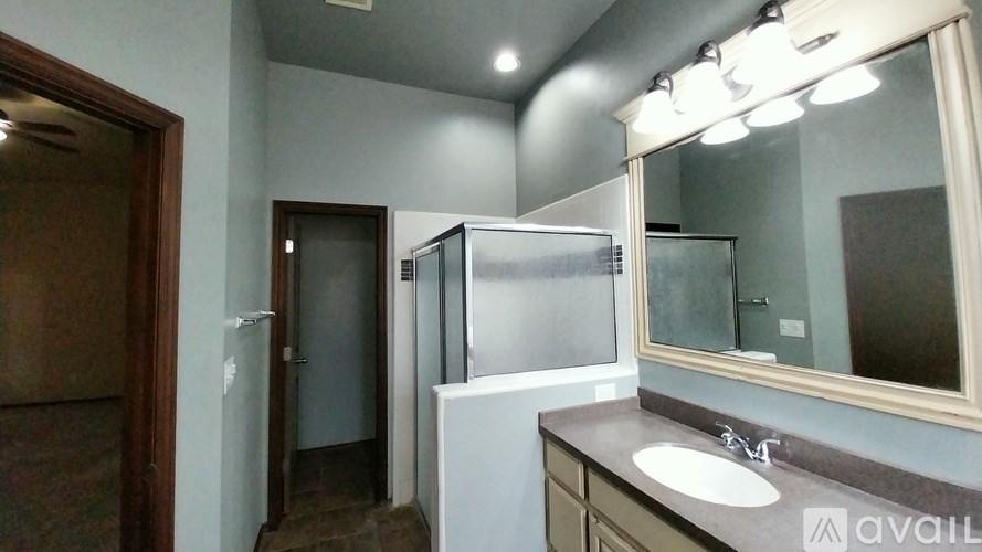 A bathroom with a sink, mirror, and a shower stall.