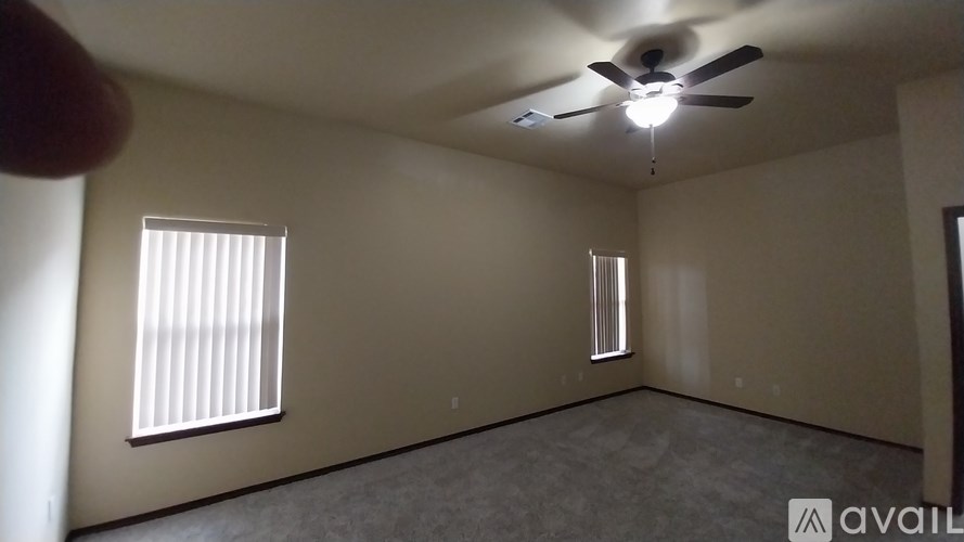 A room with a ceiling fan and two windows.