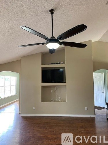 A room with a ceiling fan and a television mounted on the wall.