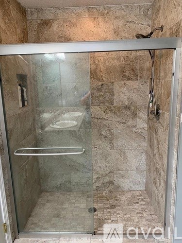 A shower with a glass door and a glass shelving unit.