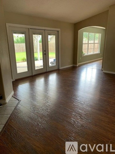 A room with wooden flooring and a large window.