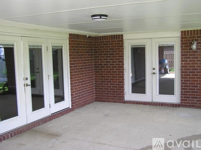 A patio with a white ceiling and a brick wall with three doors.